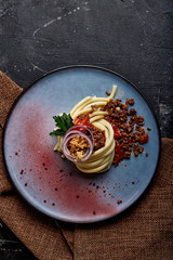 Spaghetti bolognese. Concept Italian cuisine, Spaghetti beautifully laid out on a plate and watered with Bolognese meat sauce. Blue plate, dark background.