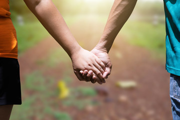 Man and woman holding hand on blurred green nature background