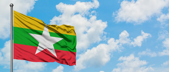 Myanmar flag waving in the wind against white cloudy blue sky. Diplomacy concept, international relations.