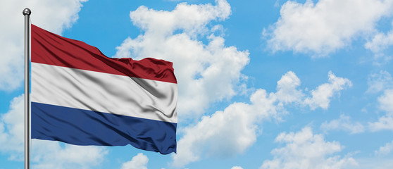 Netherlands flag waving in the wind against white cloudy blue sky. Diplomacy concept, international relations.