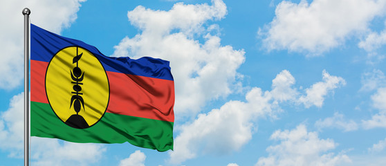 New Caledonia flag waving in the wind against white cloudy blue sky. Diplomacy concept, international relations.