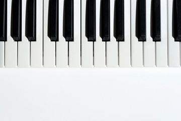 Top view of keyboard synthesizer instrument on white background with copy space under it. Black and white keys of piano.