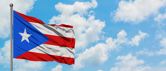 Puerto Rico flag waving in the wind against white cloudy blue sky. Diplomacy concept, international relations.