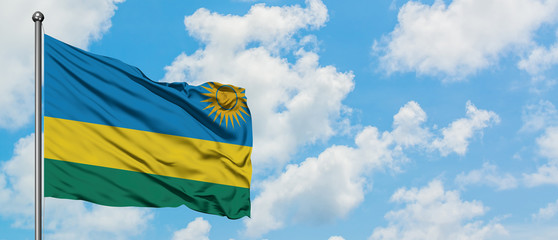 Rwanda flag waving in the wind against white cloudy blue sky. Diplomacy concept, international relations.