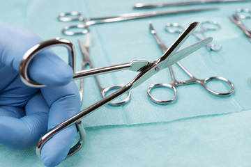 Male doctor holding bandage scissor on green background. Medical object