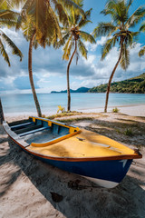 Naklejka na ściany i meble Boat under coconut palm trees on sunny day on shore of tropical beach, Seychelles islands