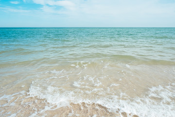 Fototapeta na wymiar Blue turquoise sea waves with sand and sky clouds