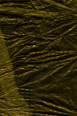 Transparent yellow plastic wrap on the black background. Plastic shopping bag texture. Reusable trash and waste.