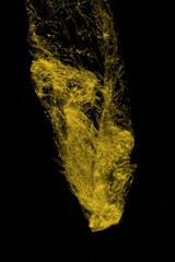 Transparent yellow plastic wrap on the black background. Plastic shopping bag texture. Reusable trash and waste.