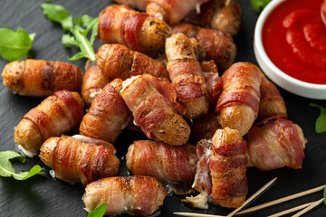 Party finger food pigs in blankets on toothpicks with ketchup sauce and wild rocket leaves