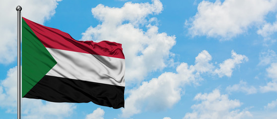 Fototapeta premium Sudan flag waving in the wind against white cloudy blue sky. Diplomacy concept, international relations.
