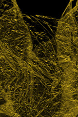 Transparent yellow plastic wrap on the black background. Plastic shopping bag texture. Reusable trash and waste.