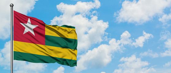 Togo flag waving in the wind against white cloudy blue sky. Diplomacy concept, international relations.
