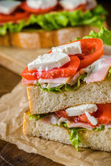 Delicious sandwich and lager beer on wooden table with dark background.