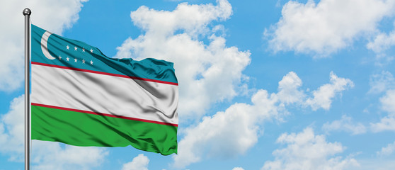 Uzbekistan flag waving in the wind against white cloudy blue sky. Diplomacy concept, international relations.