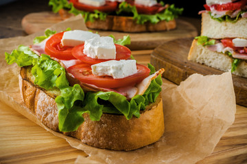 Delicious sandwich and lager beer on wooden table with dark background.