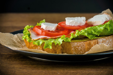Delicious sandwich and lager beer on wooden table with dark background.