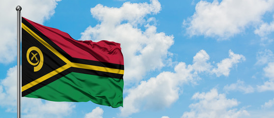 Vanuatu flag waving in the wind against white cloudy blue sky. Diplomacy concept, international relations.