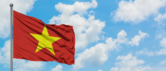 Vietnam flag waving in the wind against white cloudy blue sky. Diplomacy concept, international relations.
