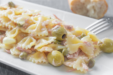 An italian pasta dish (farfalle type) topped with tuna capers and olives