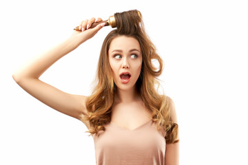 Fototapeta premium surprised shocked young woman with long beautiful hair, combs them and open her mouth in amazement. the concept of hair care