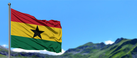 Ghana flag waving in the blue sky with green fields at mountain peak background. Nature theme.