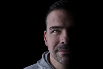 Studio portrait of a serious man looking at the camera. Isolated on black background. Horizontal. Copyspace.