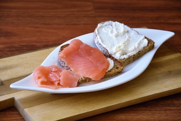 slices of bread with salmon fillet and quark on a white plate