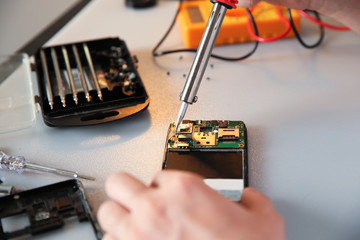 Technician repairing mobile phone at table, closeup