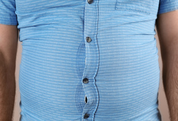 Overweight man with large belly in tight shirt , closeup