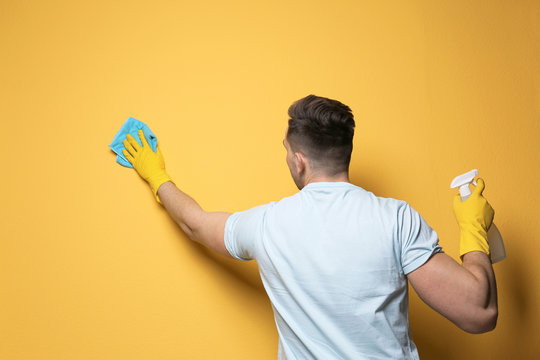 Man cleaning color wall with rag and sprayer