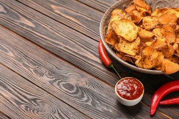 Plate of sweet potato chips, sauce and hot pepper on wooden table. Space for text