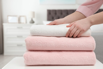 Woman stacking clean towels on table in bedroom