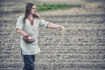 A young peasant sows the field with grain