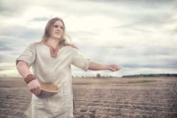 A young peasant sows the field with grain