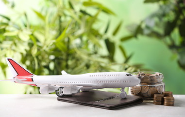 Plane model, passport and coins on table against blurred background. Space for text