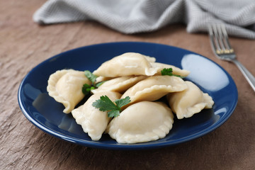 Plate of tasty dumplings served with parsley on table