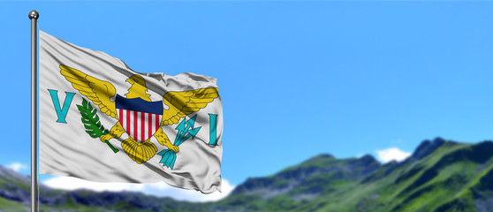 United States Virgin Islands flag waving in the blue sky with green fields at mountain peak background. Nature theme.