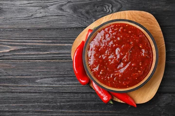 Velvet curtains Hot chili peppers Bowl of hot chili sauce with red peppers on dark wooden background, top view. Space for text