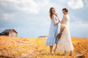 Two girls in dresses in autumn field