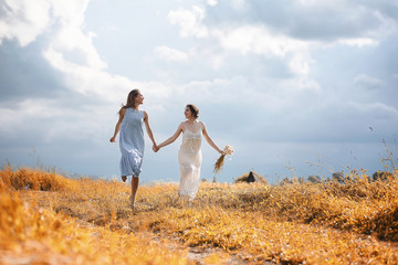 Fototapeta na wymiar Two girls in dresses in autumn field