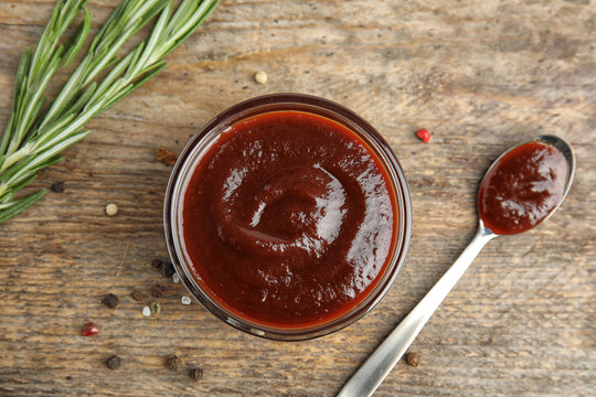 Flat lay composition with barbecue sauce on wooden background