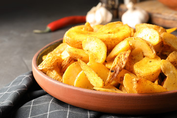 Plate of delicious oven baked potatoes on table, closeup