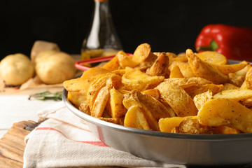 Dish of delicious oven baked potatoes on table, closeup
