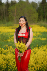 Naklejka na ściany i meble pretty brunette girl with long hair wearing long latex dress in the yellow summer field. young woman on the nature alone.