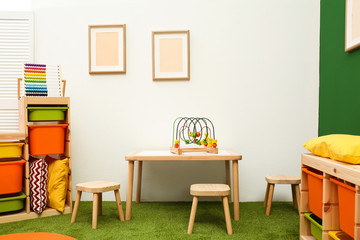 Stylish playroom interior with table and stools