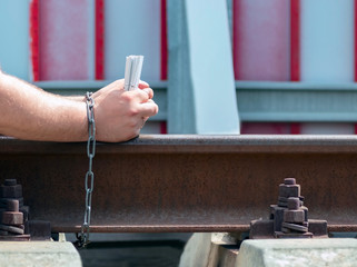 Hands of men with cigarettes, chained to the railroad tracks. The concept of dependency of a person...