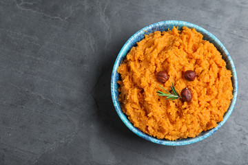 Bowl with mashed sweet potatoes on grey background, top view. Space for text