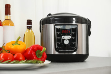 Modern multi cooker and products on table in kitchen