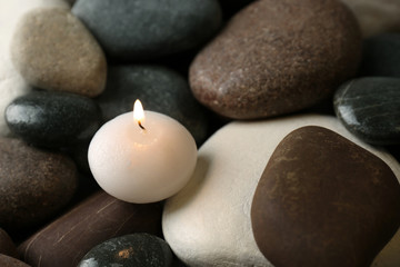 Obraz na płótnie Canvas Small burning candle on beautiful spa stones, space for text